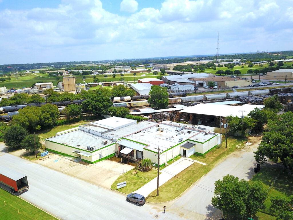 Aerial view of a warehouse building with multiple loading docks, nearby power lines, and adjacent to a nearby train