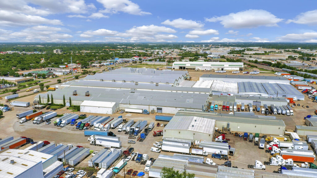 Aerial view of 4040 Forest Lane showing multiple tin-roofed warehouse buildings with numerous trailers parked outside