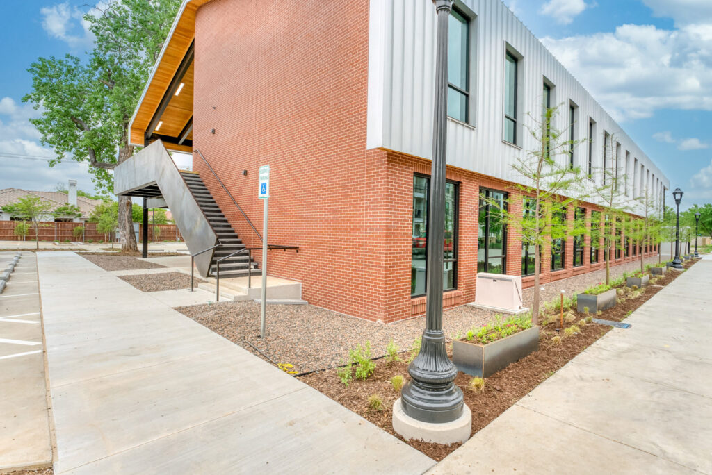 Exterior view of the staircase leading up to the second floor balcony with a black lamp post and red brick wall