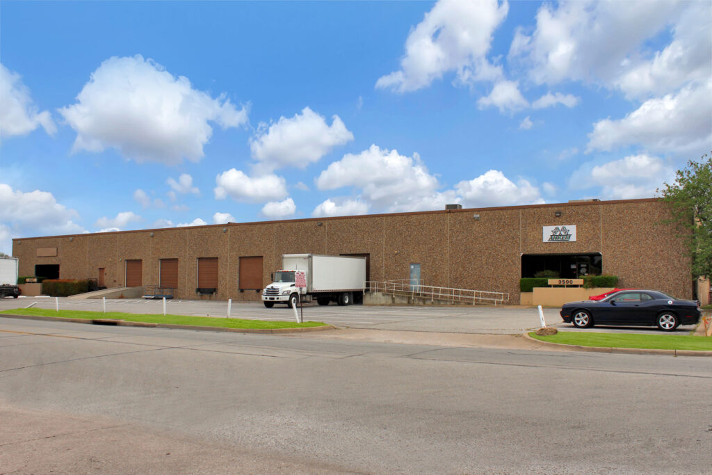 Ground-level view from the street of one building in the Valwood Portfolio with a white truck parked in a loading dock