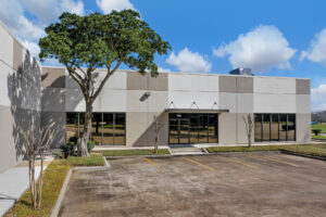 Close-up, ground level view of 700 Industrial Boulevard with a door entrance and multiple large windows