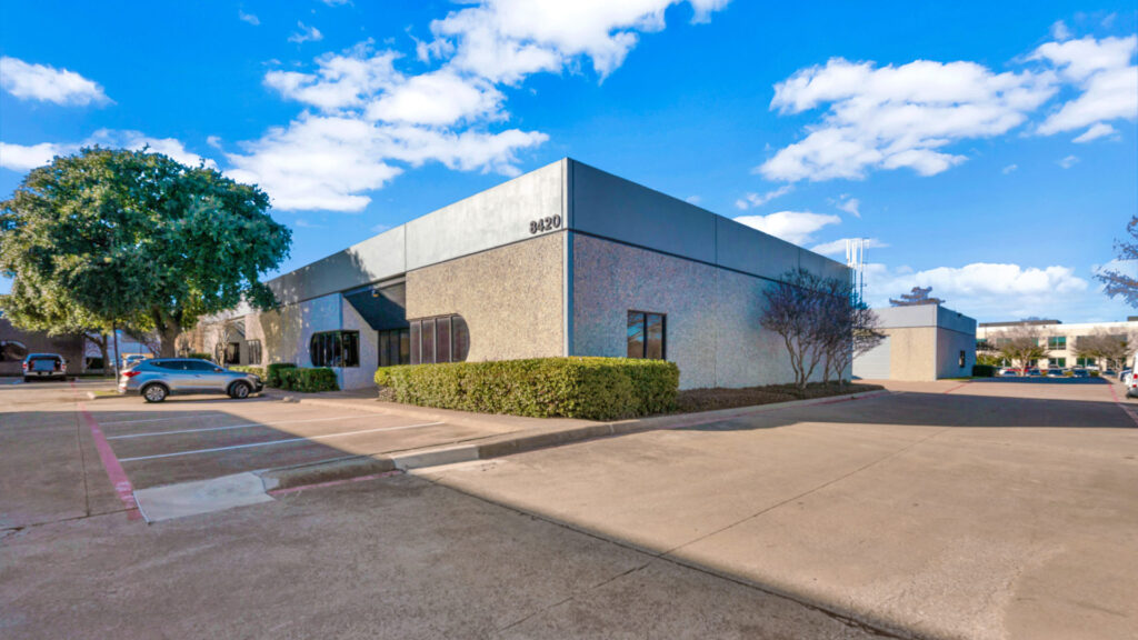 Corner view of the Commerce Business Park with small shrubs in front of the windows and multiple parking spaces